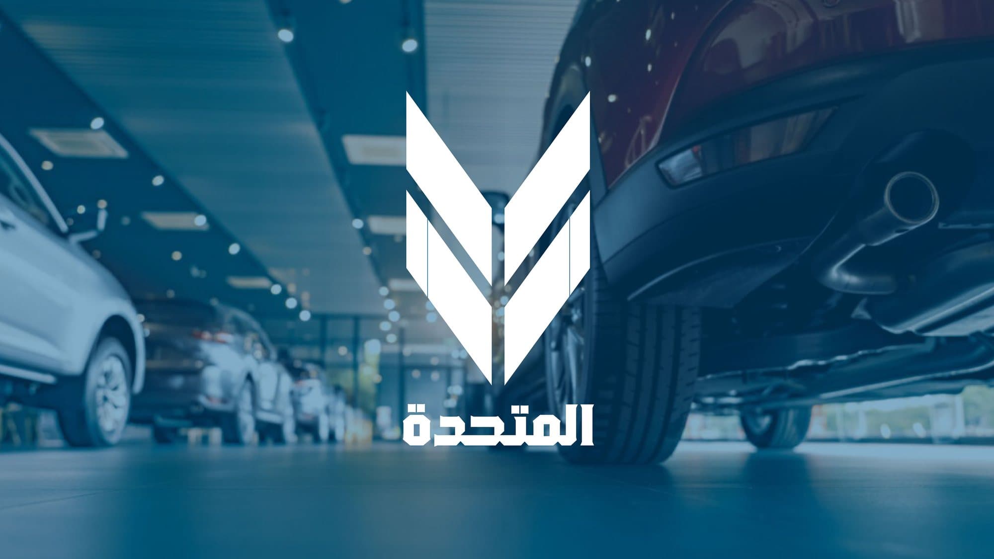 The Al Motaheda mark, a white M built from tyre tread, over a dark blue car showroom.